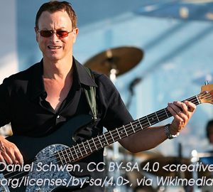 gary sinise. a man on stage with a guitar and a band with a drummer behind him